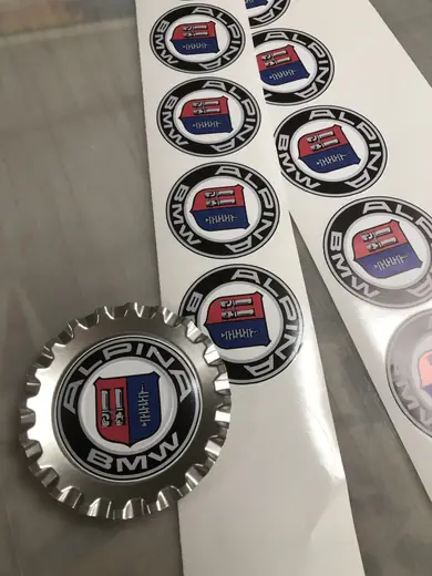 Round badge-style custom stickers next to a chrome-look emblem